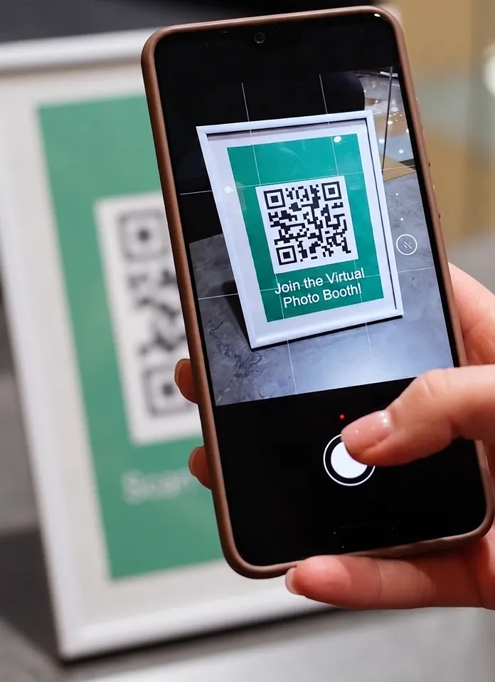 Hand holding a phone scanning a Virtual Booth QR code