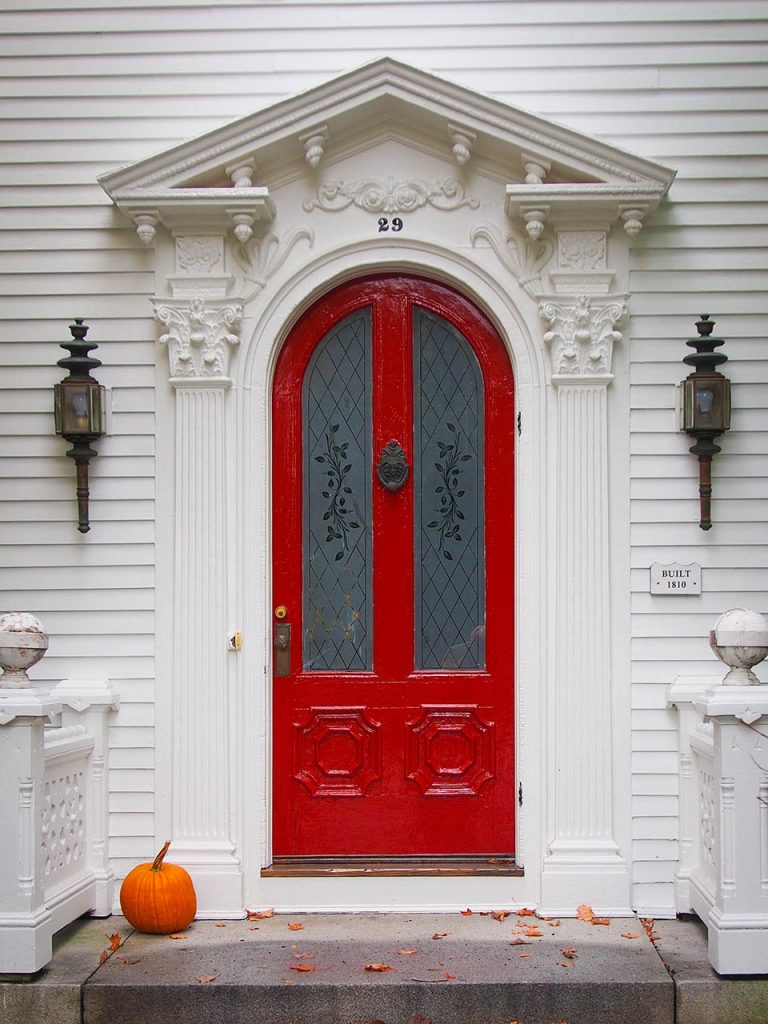 red door on white house with pumpkin on steps photo booth background