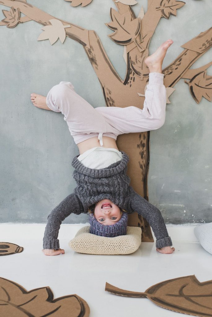 child at home doing headstand in front of photo booth