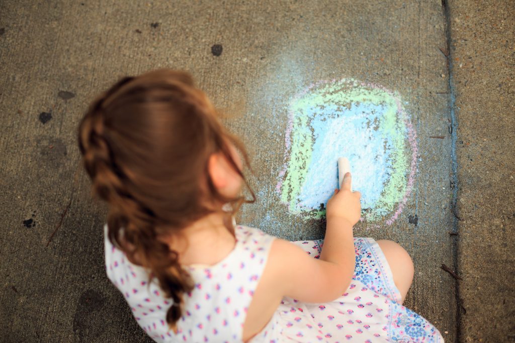 girl playing at home with sidewalk chalk