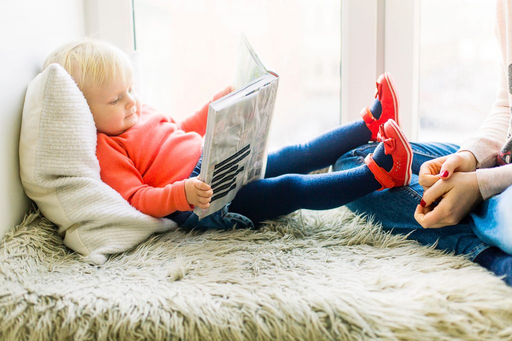 child at home reading book with mother