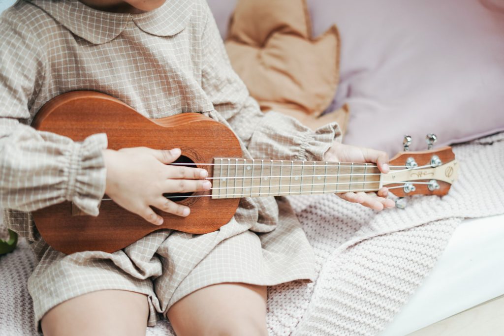 little girl playing ukulele